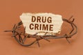 On a brown surface, barbed wire and a cardboard sign with the inscription - Drug Crime