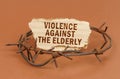 On a brown surface, barbed wire and a cardboard sign with the inscription - Violence against the elderly Royalty Free Stock Photo