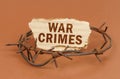 On a brown surface, barbed wire and a cardboard sign with the inscription - War Crimes Royalty Free Stock Photo