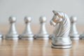 Concept of leadership, think different and recruitment employee. Knight chess leading pawns on wooden table. Leadership skills