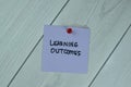 Concept of Learning Outcomes write on sticky notes isolated on Wooden Table Royalty Free Stock Photo
