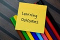 Concept of Learning Outcomes write on sticky notes isolated on Wooden Table Royalty Free Stock Photo