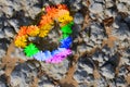 Concept of LGBT . rainbow colored Heart of flowers on a sandstone rock background.