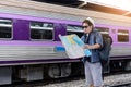 Concept life style holidays travel or journey : Young Asian backpacker man is viewing map to plan a trip at the train station Royalty Free Stock Photo