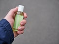 Concept of living in a new reality of coronavirus epidemic hysteria man`s hand holding sanitizer gel bottle outdoors on city