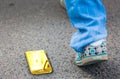 The concept of losing your smartphone. Golden cell phone lies on the ground. In the background is a blurred footsteps of a woman Royalty Free Stock Photo