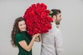 Romantic young man and woman posing with a bouquet of red roses over white background. Royalty Free Stock Photo