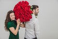 Romantic young man and woman posing with a bouquet of red roses over white background. Royalty Free Stock Photo