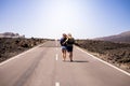 Concept of love forever toggether with young beautiful people couple viewed from back walking alone on a long straight road at the