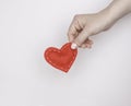 Concept of love, heart treatment. A woman`s hand holds a red rag heart. Light background