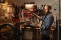 Concept of maintenance of bike. Concentrated cycling mechanic male repairing bicycle wheel working in garage with dark Royalty Free Stock Photo