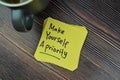 Concept of Make Yourself A Priority Reminder write on sticky notes isolated on Wooden Table Royalty Free Stock Photo