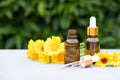 Concept of making natural cosmetics at home - dropper bottles with calendula oil against green leaves as natural background