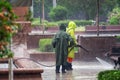 The concept of meaningless work. Two workers wash the sidewalk during a very heavy rain