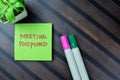 Concept of Meeting Postponed write on sticky notes isolated on Wooden Table
