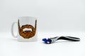 A mug with an image of a beard on it with a razor on white background. Concept for mens health, no shave november and movember