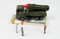 On the dollars is a toy military vehicle, next to the figures of businessmen. Royalty Free Stock Photo