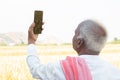 Concept of mobile phone network reception or signal problem - Elderly Indian farmer searching for good network signal near the