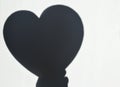 Concept modern abstract background of shadow heart in hand on a white wall