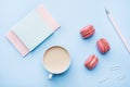 Concept morning Breakfast. Cup of coffee, macaroon cookies and notepad on blue pastel background. Flat lay style Royalty Free Stock Photo