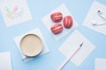 Concept morning Breakfast. Cup of coffee, macaroon cookies and notepad on blue pastel background. Flat lay style Royalty Free Stock Photo