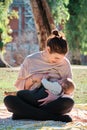 Young woman breastfeeding her son outdoors in a public park