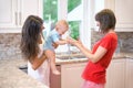 The concept of motherhood, nanny, infancy and childhood. Indoor shot in the kitchen. Two women and a baby in their arms Royalty Free Stock Photo