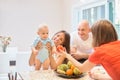 The concept of motherhood, nanny, infancy and childhood. Indoor shot in the kitchen. Two women and a child in their arms, the