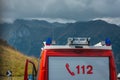 Concept of mountain rescue. Fire truck or rescue team with visible emergency number parked in front of a majestic mountain