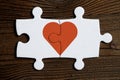 The concept of mutual love. Pieces of a connected white puzzle with red heart on a wooden background Royalty Free Stock Photo