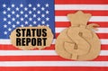 On the US flag there is a cardboard figure of a money bag and a cardboard with the inscription - STATUS REPORT Royalty Free Stock Photo