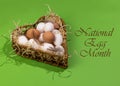 Concept for National Egg Month. The name of the holiday is written over the image. White and brown eggs lie on shavings in a heart Royalty Free Stock Photo