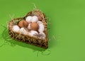 Concept for National Egg Month. White and brown eggs lie on shavings in a heart-shaped basket. Copy space Royalty Free Stock Photo