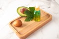 The concept of natural organic avocado oil for facial skin care in a glass bottle on a wooden tray with avocado fruit Royalty Free Stock Photo