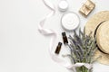 Concept of natural spa cosmetics. Open jar of cream, white cosmetics bottles, soap, straw hat and bouquet of lavender on white Royalty Free Stock Photo