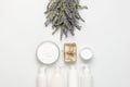 Concept of natural spa cosmetics. Open jar of hand, face or body cream, white cosmetics bottles, soap and lavender on white
