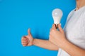 Concept of new idea and innovation with light bulbs. LED lamp in female hands on a blue background Royalty Free Stock Photo