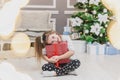 Light photo of cute kid sitting with gift in hands, like a little gnome in christmas decorated room. Royalty Free Stock Photo