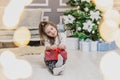 Light photo of cute kid sitting with gift in hands, like a little gnome in christmas decorated room. Royalty Free Stock Photo