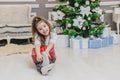 Light photo of cute kid sitting with gift in hands, like a little gnome in christmas decorated room. Royalty Free Stock Photo