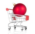 Concept of New Year`s bustle and shopping. Christmas red ball in shopping cart isolated on white