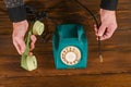 the handset and the dangling wire of the landline phone in his hand. on a table made of wooden boards. the concept of no Royalty Free Stock Photo