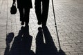 Elderly couple, silhouettes and shadows of two people walking with cane and handbag on the street