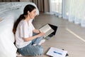 Concept of online courses and online learning. A young woman is sitting on the floor reading a book. Royalty Free Stock Photo