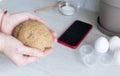 The concept of online lessons in the preparation of cookies. A ball of dough in female hands against the background of ingredients