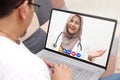 Concept of online medical healthcare, shows laptop display with Asian muslim female doctor smiling, telehealth, telemedicine video