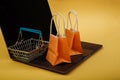 Concept of online shopping. Orange bags and shopping cart on laptop