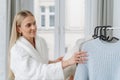 Woman in terry bathrobe choosing clothes in open garderobe