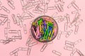 The concept of order and chaos. Chaotic scattered silvery paper clips on pink background and ordered stacked multicolored paper cl