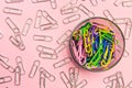 The concept of order and chaos. Chaotic scattered silvery paper clips on pink background and ordered stacked multicolored paper